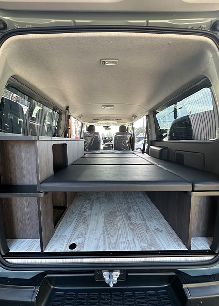 後部から見たカスタムバンの室内。寝台、収納ユニット、運転席まで一望できる広々とした空間
