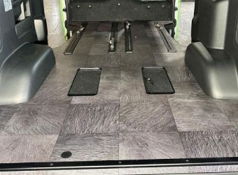ハイエースの荷室フロア。木目調タイル張りと金属製レールで、汚れや水滴を拭き取りやすい清潔な内装